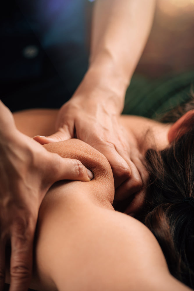 A therapist working deeply into a guest's shoulder