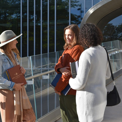 Three friends chatting outdoors, holding their Dreambooks
