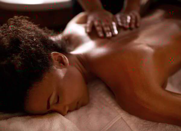 A therapist's hands massaging a guest's back as she rests face down