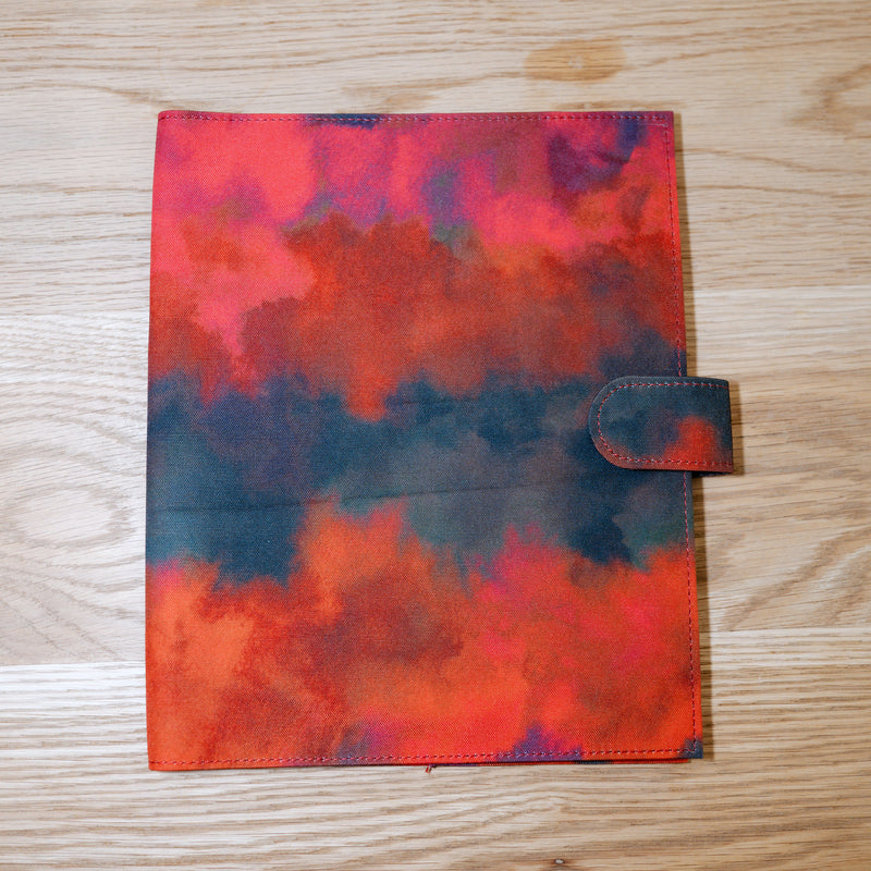 A cover in watercolor reds and deep blue-black