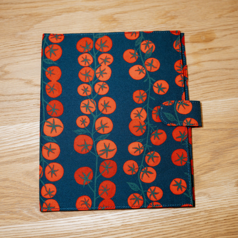 A navy cover printed with vines of bright red tomatoes