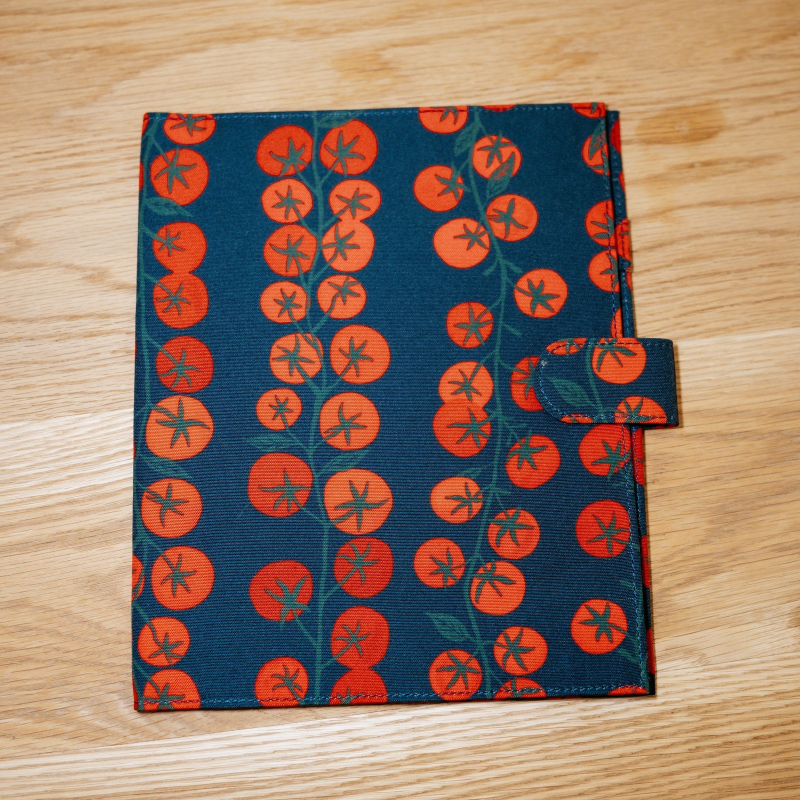 The Heirloom cover: navy printed with vines of bright red tomatoes