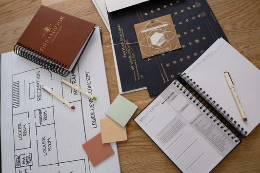 The Saddle 2027 Dreambook, an open Weekly Alignment spread, and a Two Moon Star Chart on a table