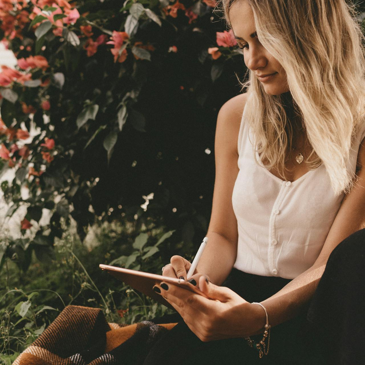 Woman using a tablet outdoors with flowers in the background