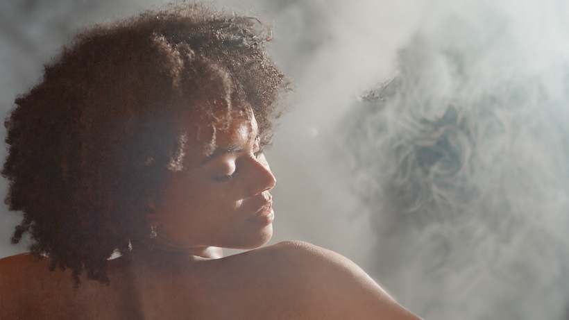 A guest with her eyes closed in the warm steam room at The Dragontree Sanctuary